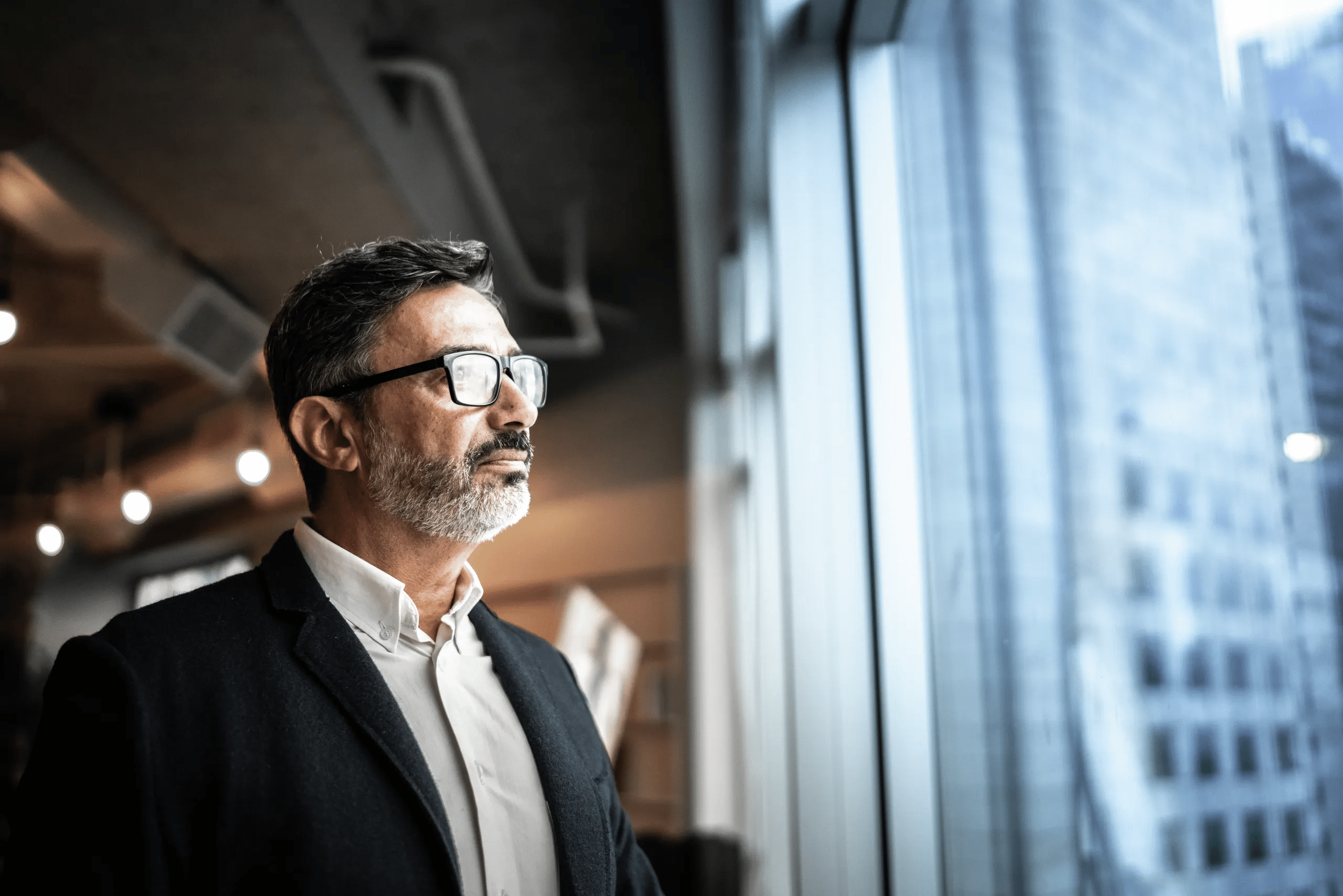 A business professional looking through a window.