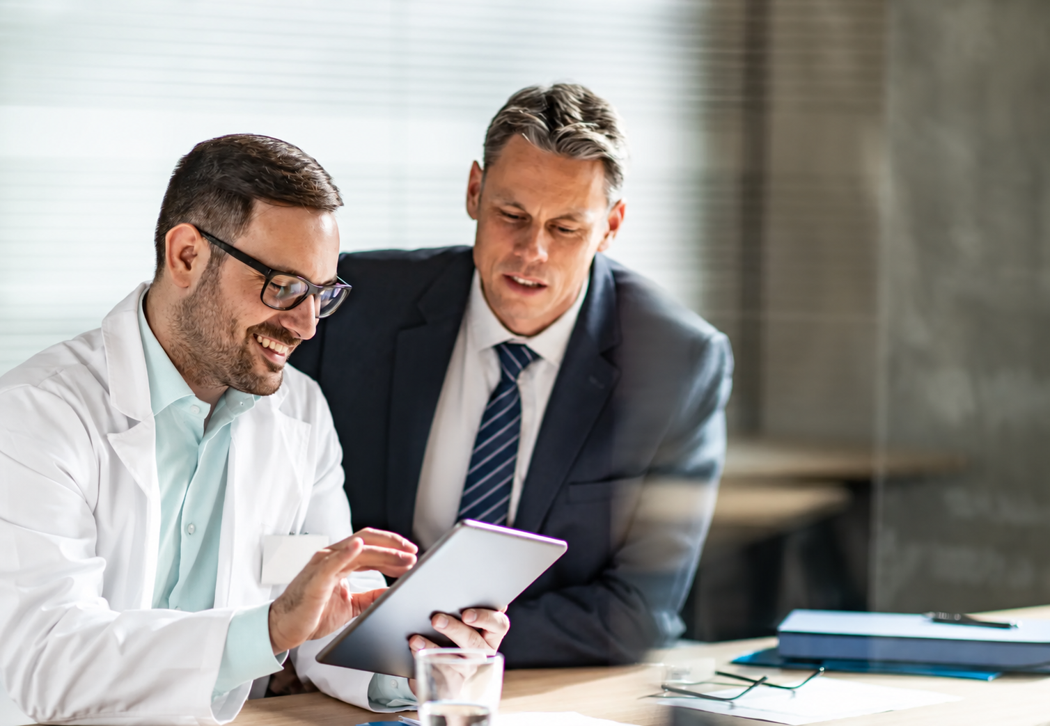 A clinician and business-dressed colleague reviewing a tablet together.