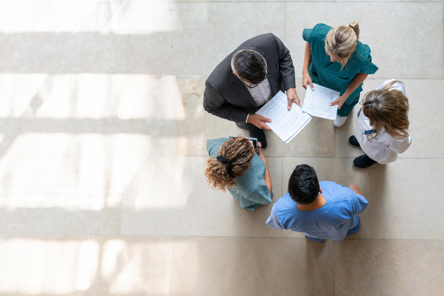 An overhead discussion with care-team participants and a business-dressed colleague.
