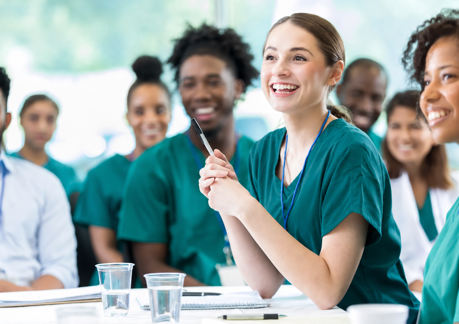 Healthcare professionals in teal scrubs participating in a learning session.